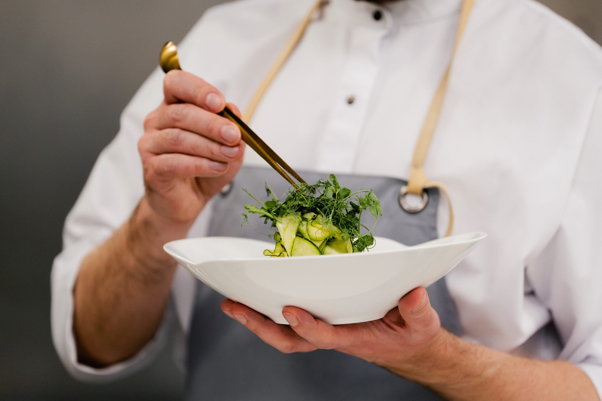 The chef finishing a dish with fresh greens